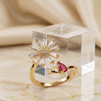 Gold plated adjustable sunflower ring featuring baguette zircons and pear cut ruby red stone accent by Trivo Essentials