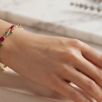 Gold plated tulip bracelet with oval ruby red stones and green marquise leaf gemstones by Trivo Essentials