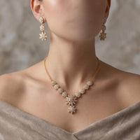 Gold plated floral zircon necklace set with matching dangle tops earrings on display stand by Trivo Essentials