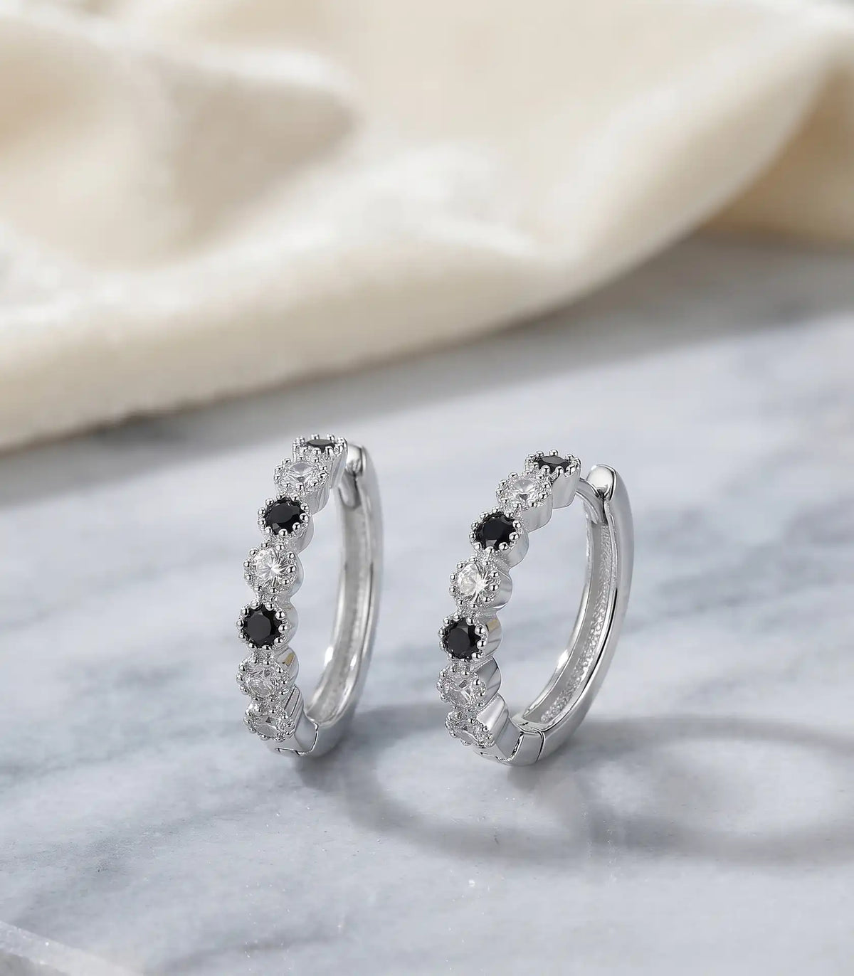 Rhodium silver huggie hoop earrings with alternating black and clear cubic zirconia stones by Trivo Essentials